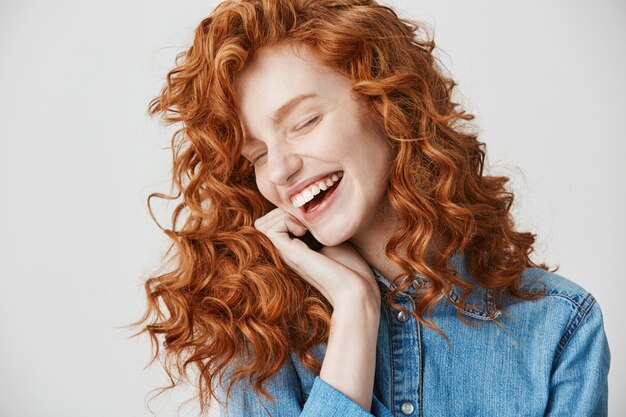 Portret van mooie schattige gember meisje lachen lachend met gesloten ogen.