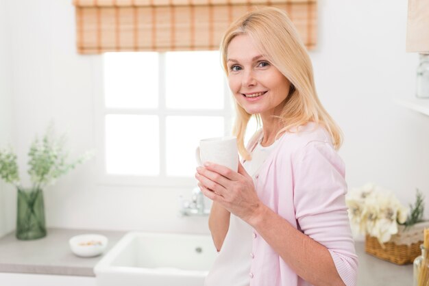 Portret van mooie volwassen vrouw in de keuken