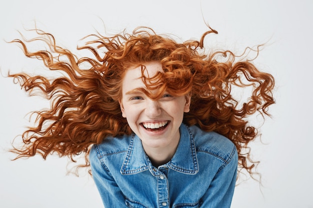 Portret van mooie vrolijke roodharige vrouw met vliegende krullend haar lachend lachen.