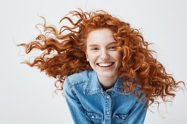 Portret van mooie vrolijke roodharige vrouw met vliegende krullend haar lachend lachen.