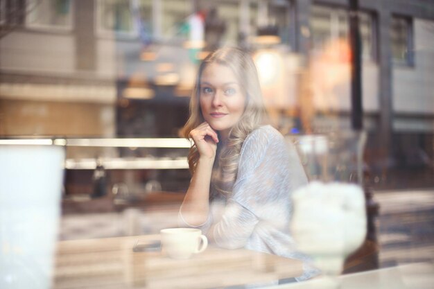 portret van mooie vrouw door een glas van een café