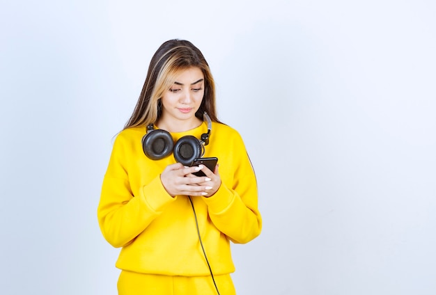 Portret van mooie vrouw met koptelefoon met behulp van mobiele telefoon