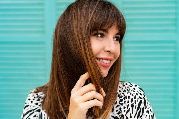 Gratis foto portret van mooie vrouw poseren over blauwe muur close-up.