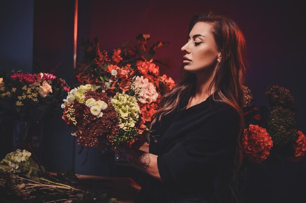 Portret van mooie vrouwelijke bloemist met boeket in handen bij floristische winkel.