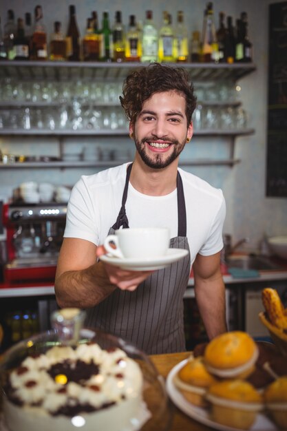 Portret van ober serveert een kopje koffie bij teller