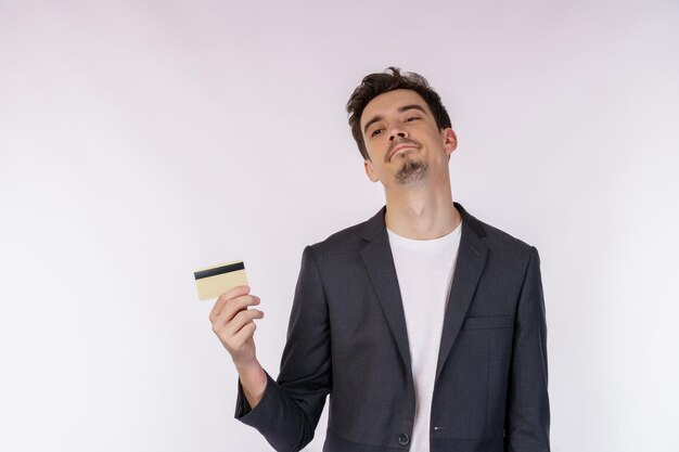 Portret van ongelukkige zakenman die creditcard toont die over witte achtergrond wordt geïsoleerd