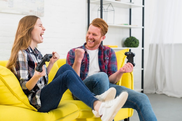 Portret van opgewekt jong paar die thuis van het videospelletje genieten