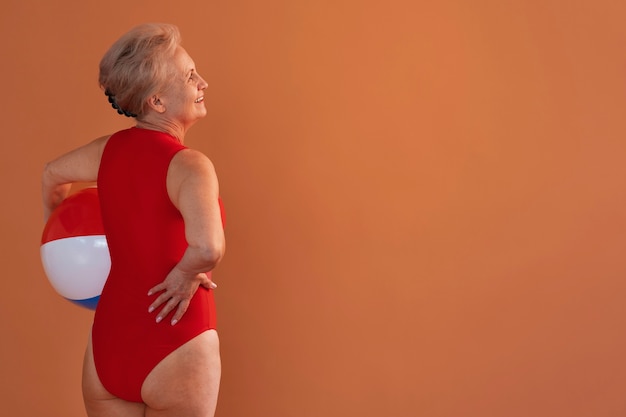 Gratis foto portret van oudere vrouw in zwempak en bal