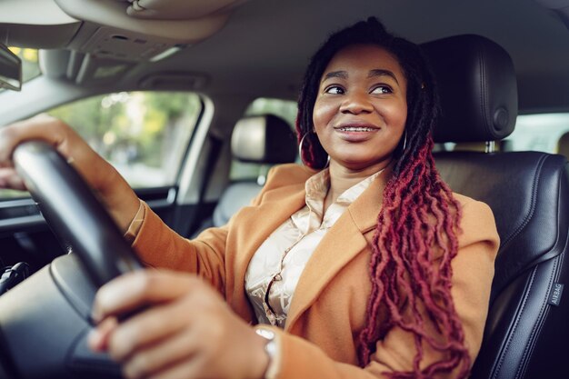 Portret van positieve Afro-Amerikaanse dame in de auto