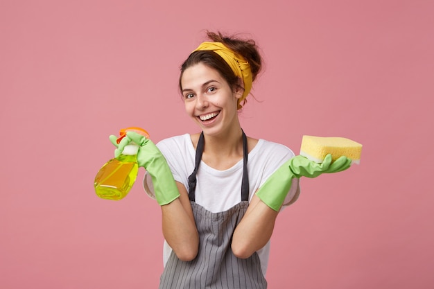 Portret van positieve emotionele jonge Europese vrouw met vrolijke gelukkige glimlach die het algemene schoonmaken doet
