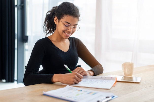 Portret van positieve jonge vrouw die op het kantoor werkt