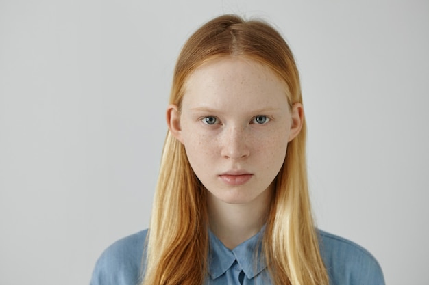 Portret van prachtige Europese tiener meisje met sproeten en blauwe ogen met haar blonde losse haren verscholen achter de oren