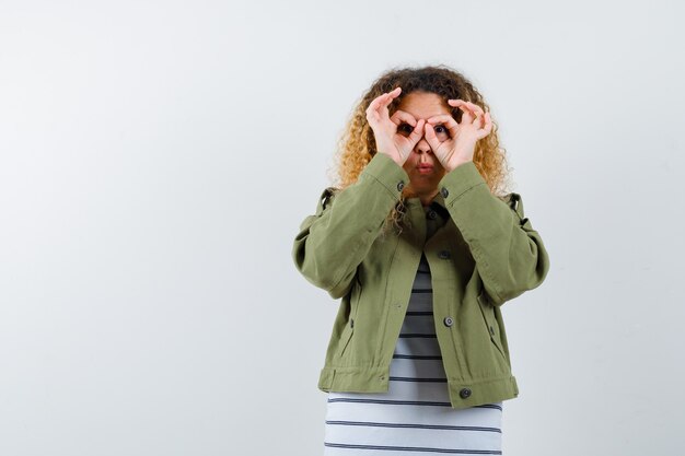 Portret van prachtige vrouw met bril gebaar in groene jas, shirt en op zoek gericht vooraanzicht