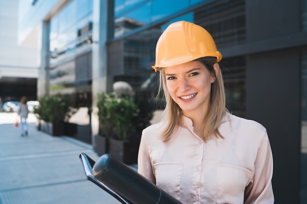 Gratis foto portret van professionele architectenvrouw die gele helm draagt en zich in openlucht bevindt. ingenieur en architect concept.