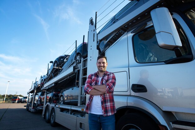 Portret van professionele lachende vrachtwagenchauffeur met gekruiste armen auto's naar de markt vervoeren