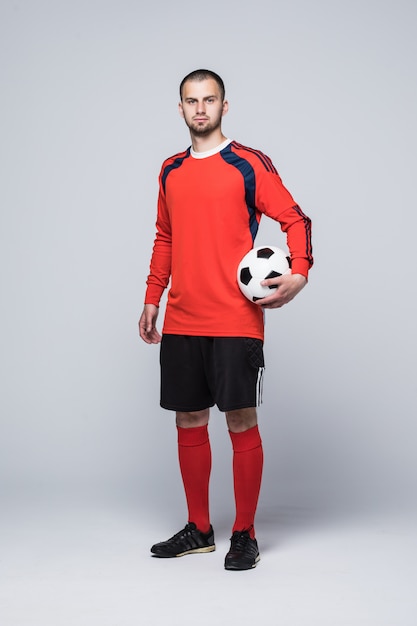 Portret van professionele voetballer in rood overhemd dat op wit wordt geïsoleerd