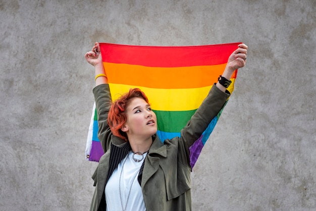 Portret van roodharige niet-binaire persoon die een lgbt-vlag houdt