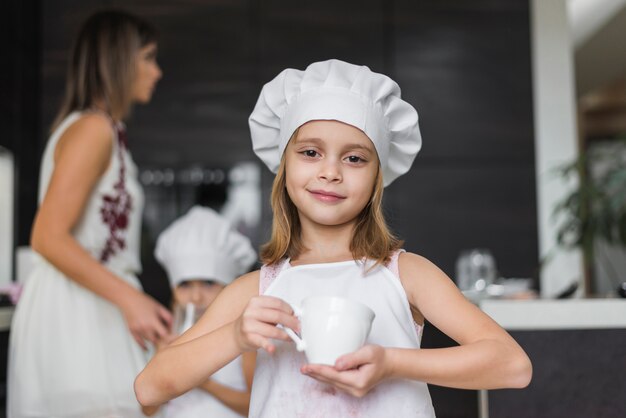 Portret van schattig klein meisje met witte kop in de keuken