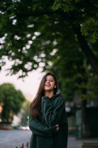 Portret van schattig meisje met lang haar kijkt naar de camera in de stad op straat