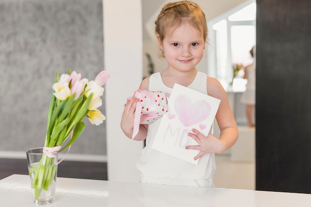 Gratis foto portret van schattig meisje permanent met geschenkdoos en wenskaart