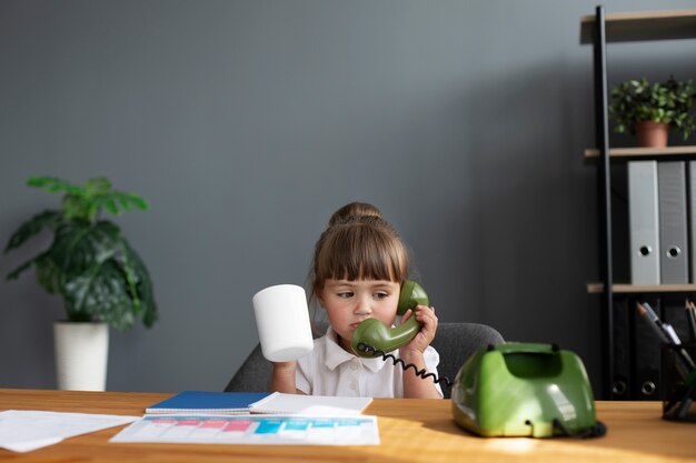 Portret van schattig meisje praten op roterende telefoon op kantoor