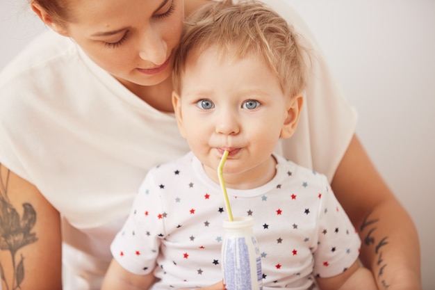 Portret van schattige blonde blauwogige babyjongen drinken met een rietje