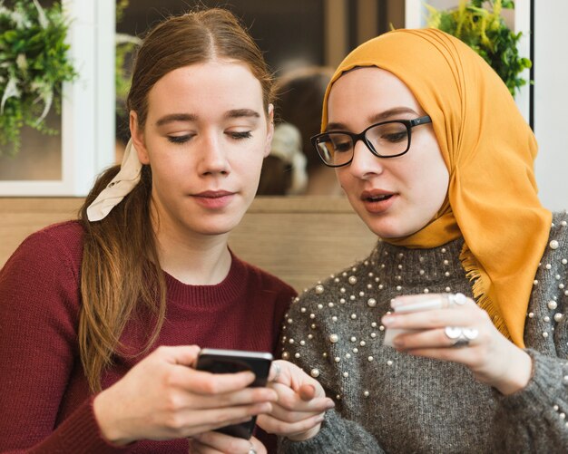 Portret van schattige jonge meisjes die een telefoon controleren