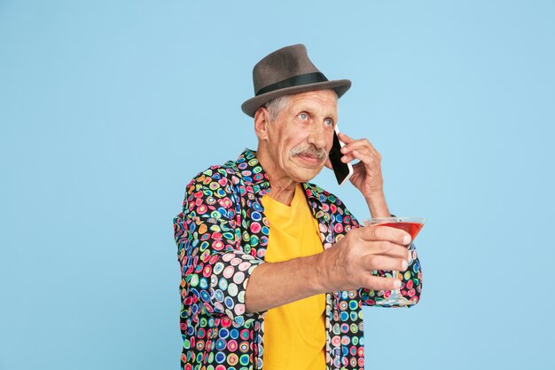 Portret van senior hipster man met behulp van apparaten, gadgets geïsoleerd op lichte studio achtergrond. Tech en vreugdevolle ouderen levensstijl concept.