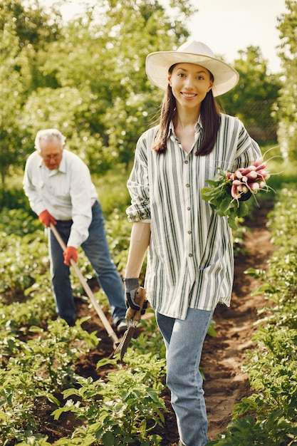 Portret van senior man in een hoed tuinieren met kleindochter