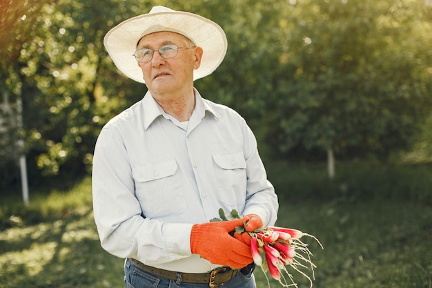 Portret van senior man in een hoed tuinieren