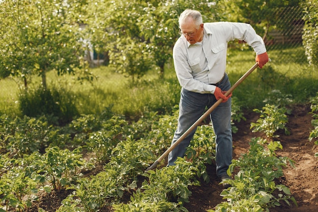 Portret van senior man in een hoed tuinieren