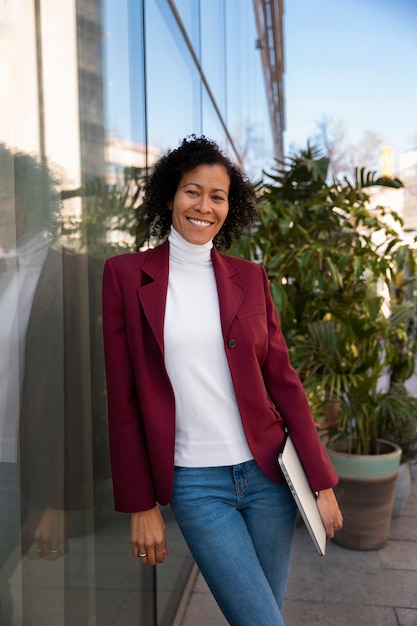 Gratis foto portret van senior vrouw in professionele blazer buitenshuis en laptop