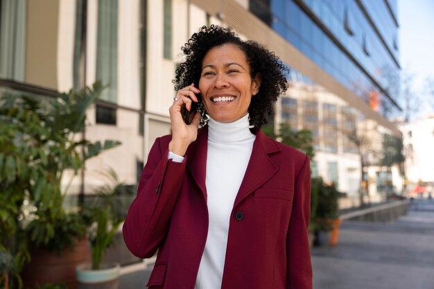 Portret van senior vrouw in professionele blazer buitenshuis en smartphone