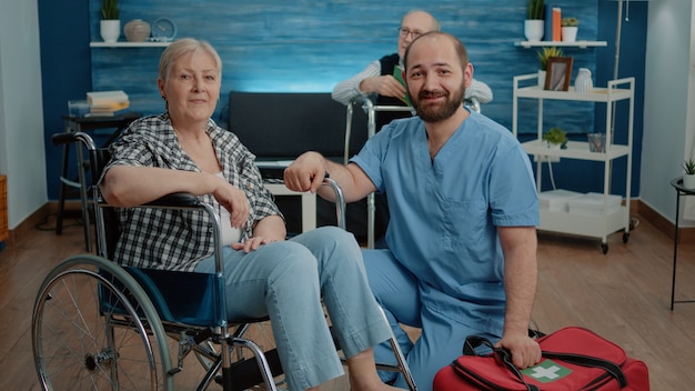 Portret van senior vrouw in rolstoel en man verpleegster