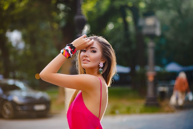 Portret van sexy elegante aantrekkelijke vrouw in roze sexy zomerjurk wandelen in straat