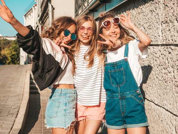 Portret van Sexy onbezorgde vrouwen die dichtbij muur in de straat stellen Positieve modellen die pret in zonnebril hebben