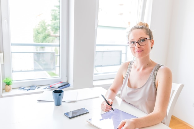 Portret van slimme grafische vrouwelijke ontwerper die grafische digitale tablet op het werk gebruiken