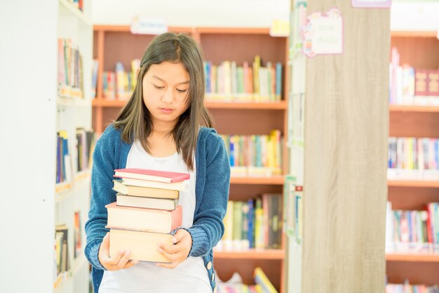 Portret van slimme student met open boek die het lezen in universiteitsbibliotheek