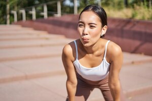 Portret van sportvrouw die hijgend een pauze neemt tijdens het joggen, zweten tijdens het hardlopen buiten
