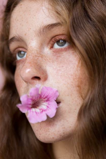 Gratis foto portret van sproeterig vrouw met bloem in haar mondclose-up