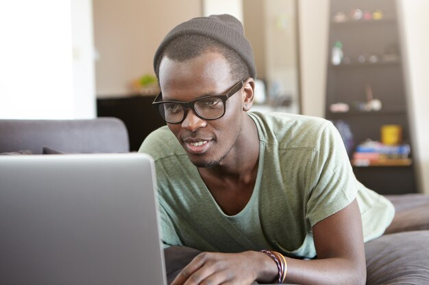 Portret van stijlvolle Afro-Amerikaanse man met laptop thuis