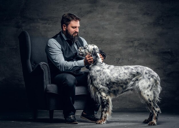 Portret van stijlvolle bebaarde man zit op een stoel en de Ierse setter hond.