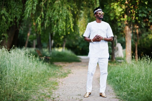 Portret van stijlvolle en rijke zwarte Afro-Amerikaanse man op witte kleding, zonnebril en hoed