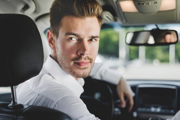 Portret van stijlvolle jonge man in de auto