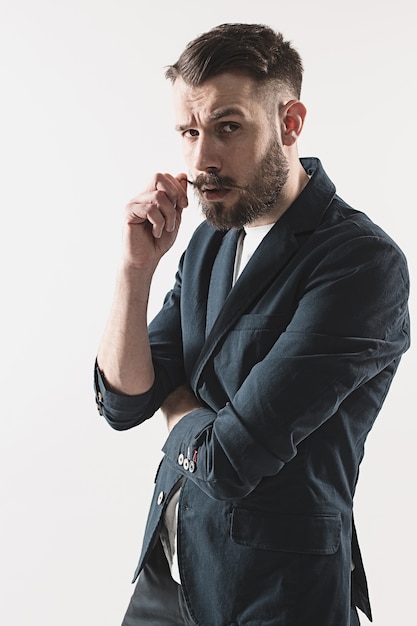 Portret van stijlvolle knappe jongeman permanent in studio tegen wit.