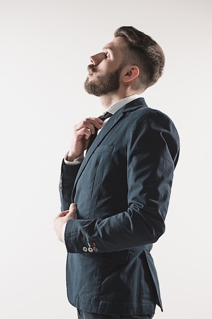 Portret van stijlvolle knappe jongeman permanent in studio tegen wit.