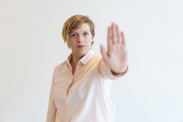 Portret van strikte medio volwassen zakenvrouw maken stop gebaar