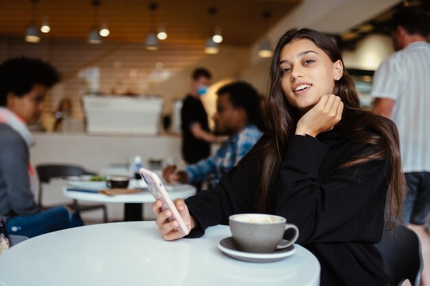 portret van student vrouw met behulp van smartphone zittend in café