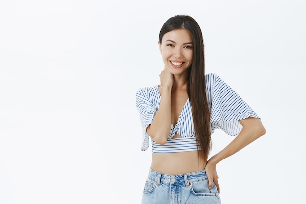 Portret van tedere en vrouwelijke aantrekkelijke jonge aziatische vrouw in trendy blouse wat betreft de hand van de halsholding op taille