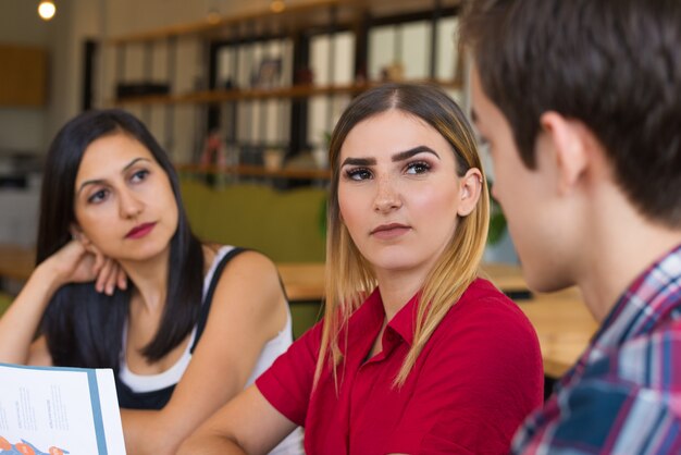 Portret van twee ernstige vrouwen die aan hun mannelijke vriend luisteren